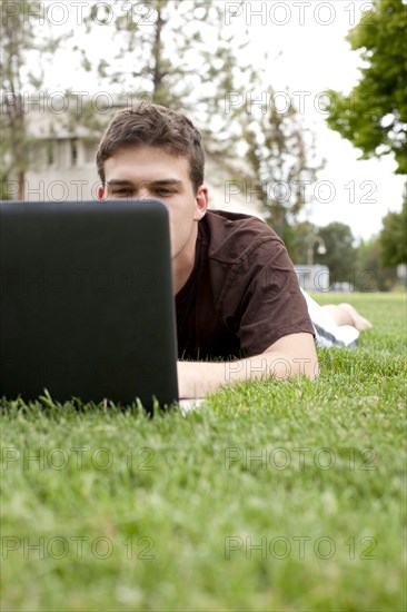 Caucasian man using laptop in grass