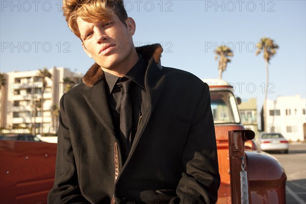 Serious Caucasian man sitting on back of truck