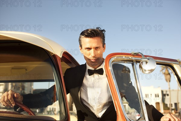 Caucasian man in tuxedo getting into car