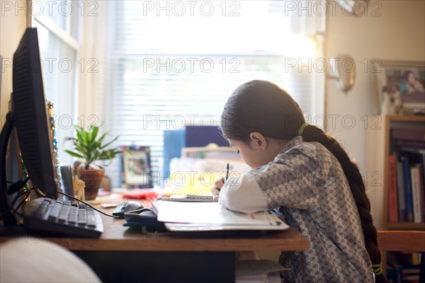 Mixed race girl doing homework at desk