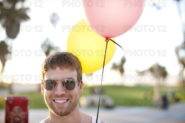 Caucasian man holding two balloons