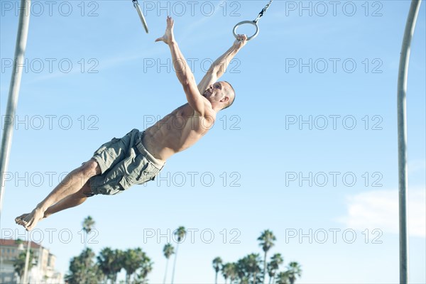 Caucasian man swinging on gymnastic rings