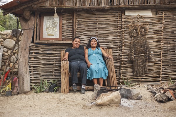 Hispanic women sitting in front of house