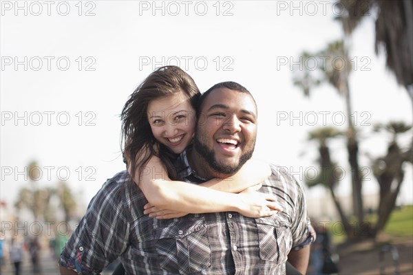 Grinning man giving wife piggyback ride