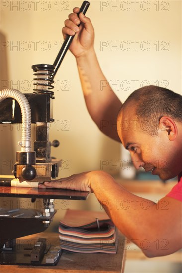 Hispanic man operating book-binding machine