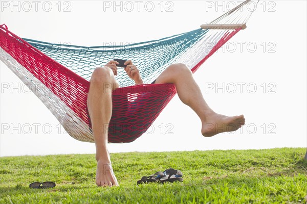 Caucasian man relaxing in hammock with cell phone