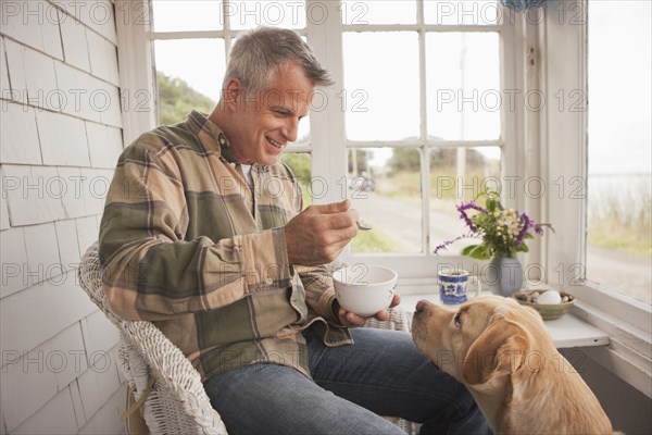 Dog watching Caucasian man eating breakfast