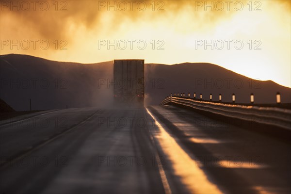 Truck driving down road on wet highway