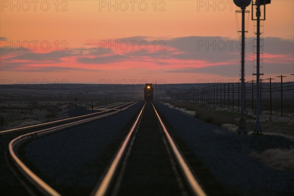 Sunset over train on tracks in rural landscape