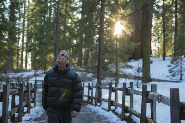 Caucasian man walking in snowy forest