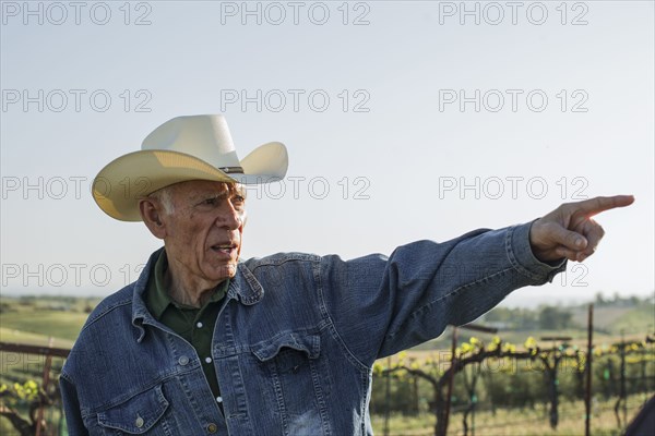 Hispanic farmer pointing in vineyard