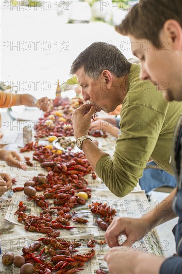 Caucasian men eating at crawfish boil