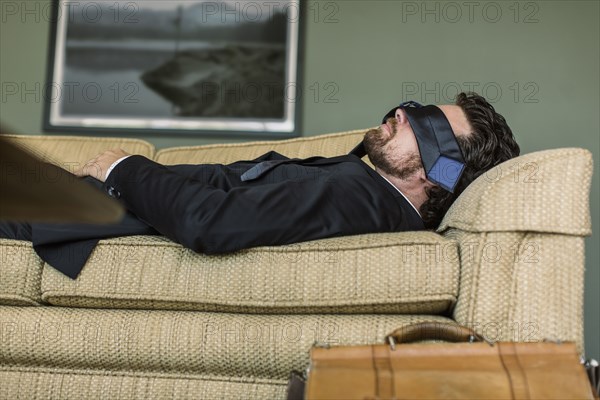 Caucasian businessman napping on sofa