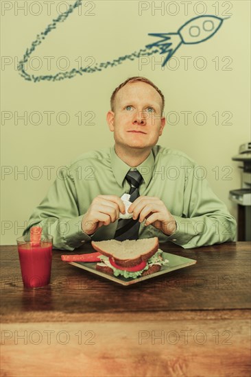 Caucasian businessman eating lunch with spaceship overhead