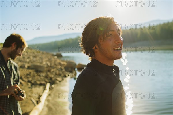 Caucasian men standing by rural lake