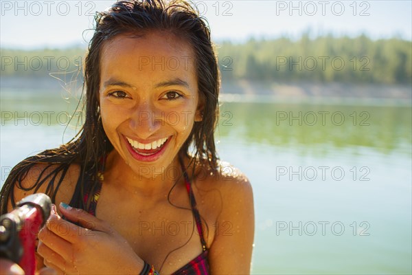 Mixed race woman smiling by rural lake