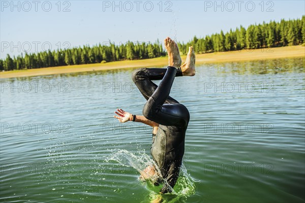 Caucasian man jumping into rural lake