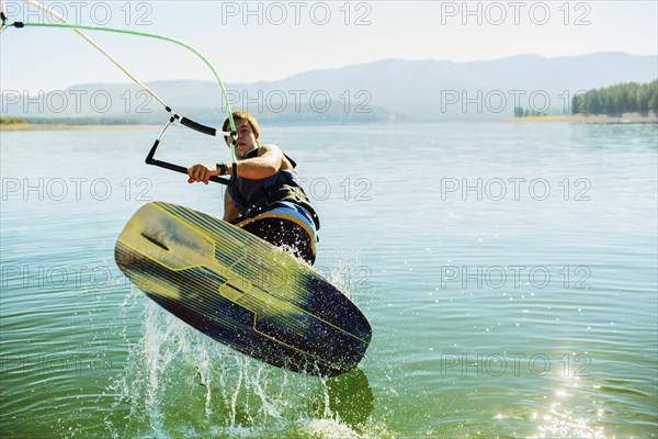 Caucasian man wakeboarding on lake