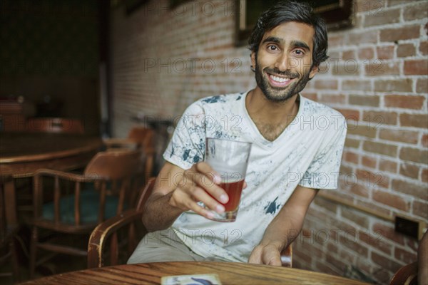 Asian man drinking beer in pub