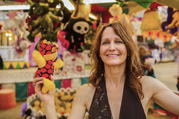 Caucasian woman holding toy at amusement park