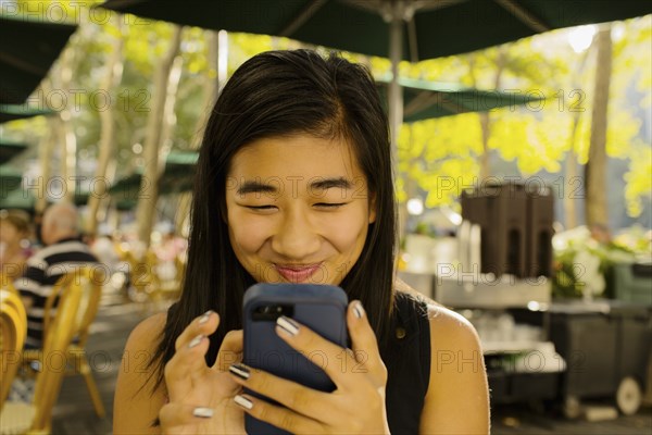 Chinese girl using cell phone on restaurant patio