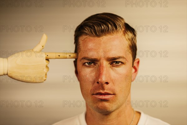 Caucasian man with wooden finger pointed at head