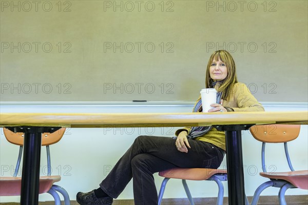 Caucasian professor sitting at table in classroom