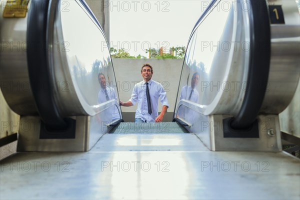 Hispanic businessman riding escalator