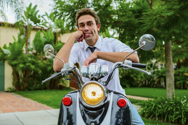 Hispanic businessman sitting on moped outdoors