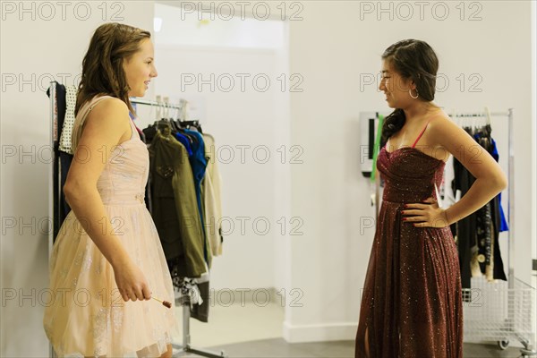 Girls trying on prom dresses in clothing store