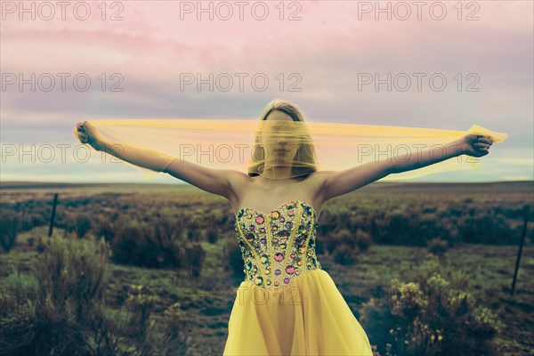 Caucasian teenage girl playing with scarf in rural field