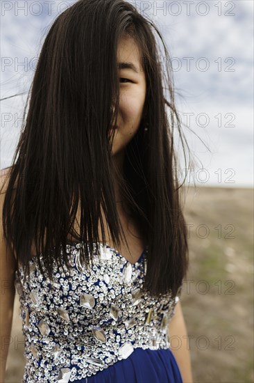Chinese teenage girl wearing gown in rural field