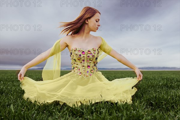 Caucasian teenage girl wearing gown in rural field