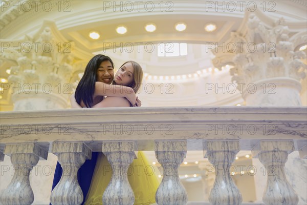 Teenage girls wearing gowns on ornate banister