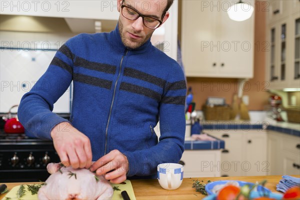 Caucasian man cooking chicken in kitchen