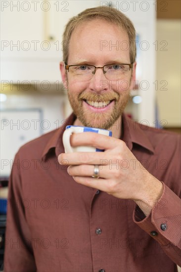 Caucasian man drinking cup of coffee in kitchen