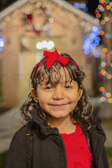 Hispanic girl smiling outside house decorated with string lights