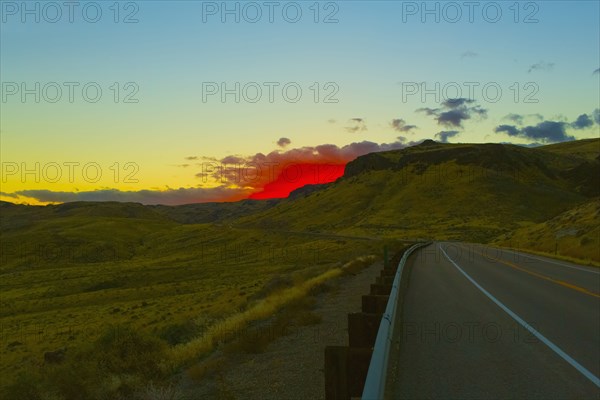 Red sunset over rural road and hillside