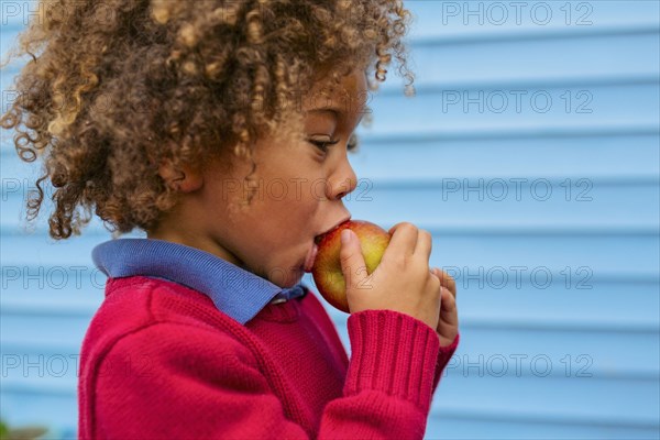 Pacific Islander boy eating apple outdoors