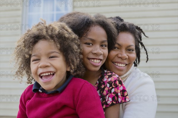 Pacific Islander mother and children hugging outdoors