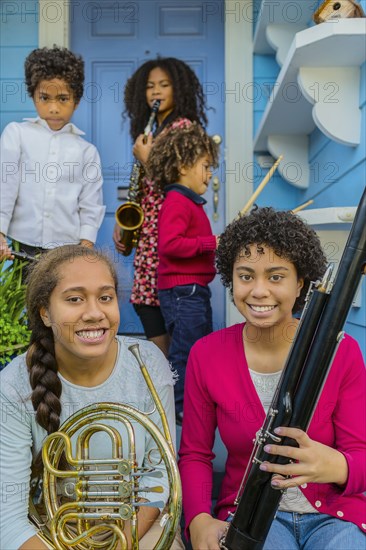 Pacific Islander family holding musical instruments on front stoop