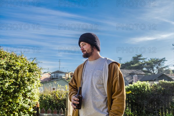Caucasian man drinking beer in backyard