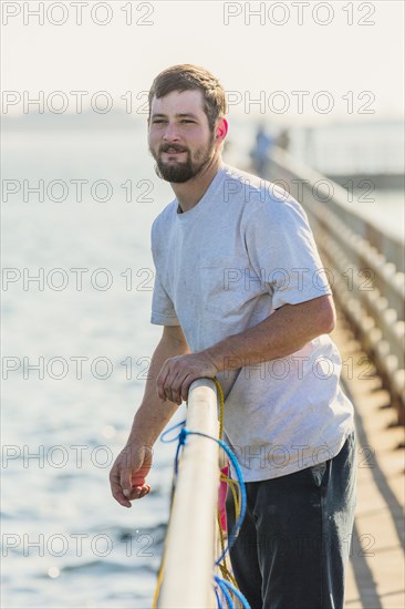 Caucasian man leaning on wooden pier