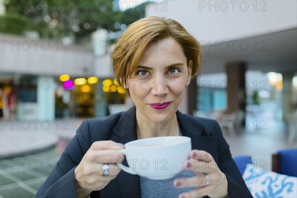 Caucasian businesswoman drinking coffee at sidewalk cafe