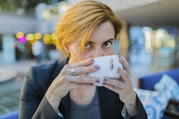 Caucasian businesswoman drinking coffee at sidewalk cafe