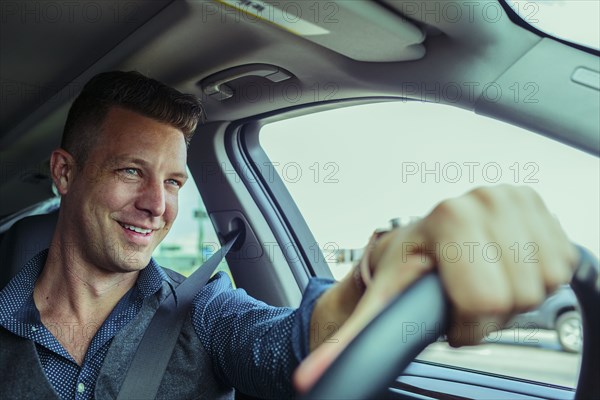 Smiling Caucasian man driving car