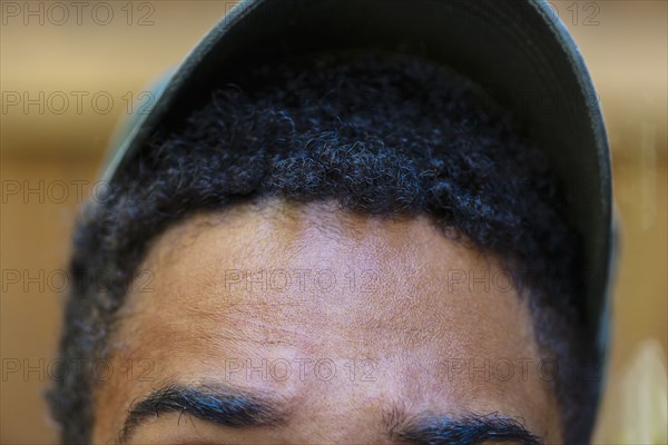 Close up of forehead and baseball cap of mixed race man