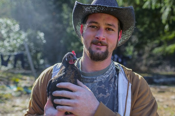 Caucasian farmer holding chicken
