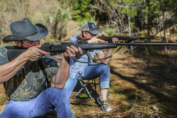 Caucasian hunters aiming guns in forest