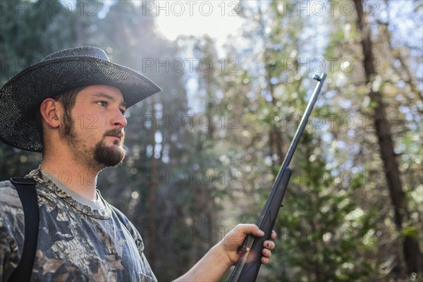 Caucasian hunter holding gun in forest